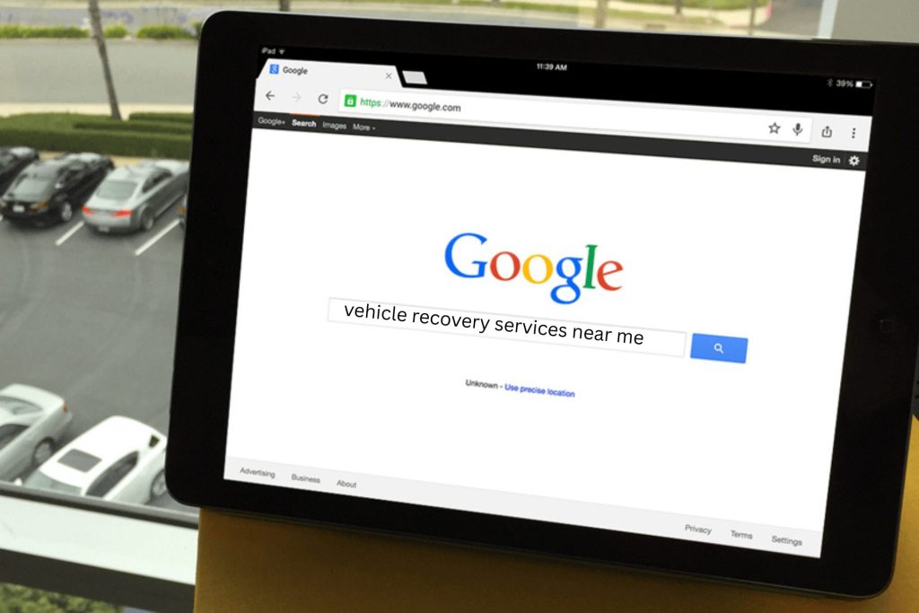 Someone searching on a black iPad for vehicle recovery services near me